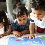 Children reading a book on the floor